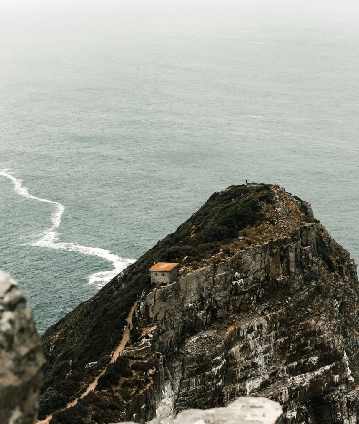 Rocky headland with a small stone hut above a grey-green sea