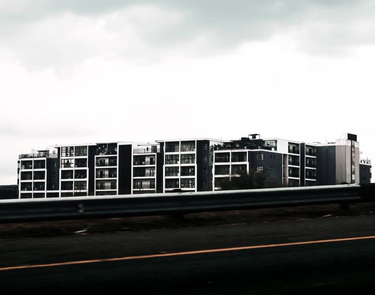 Modern apartment block seen from the roadside under a cloudy sky
