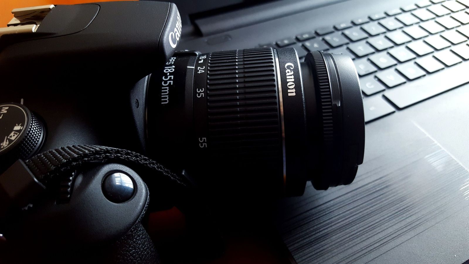 Close-up of a camera and lens resting on a laptop