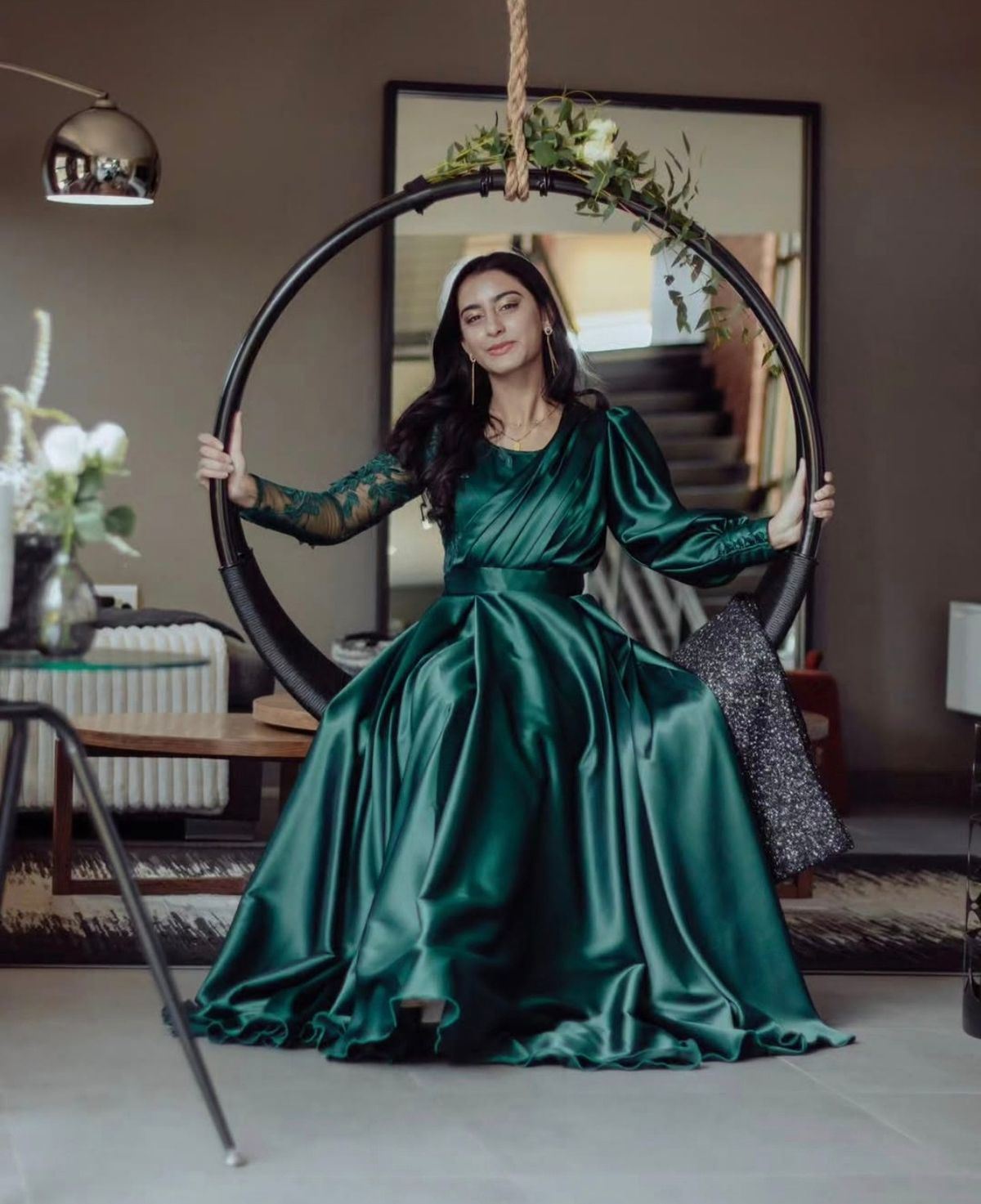Woman in an emerald satin gown seated on a hanging hoop swing