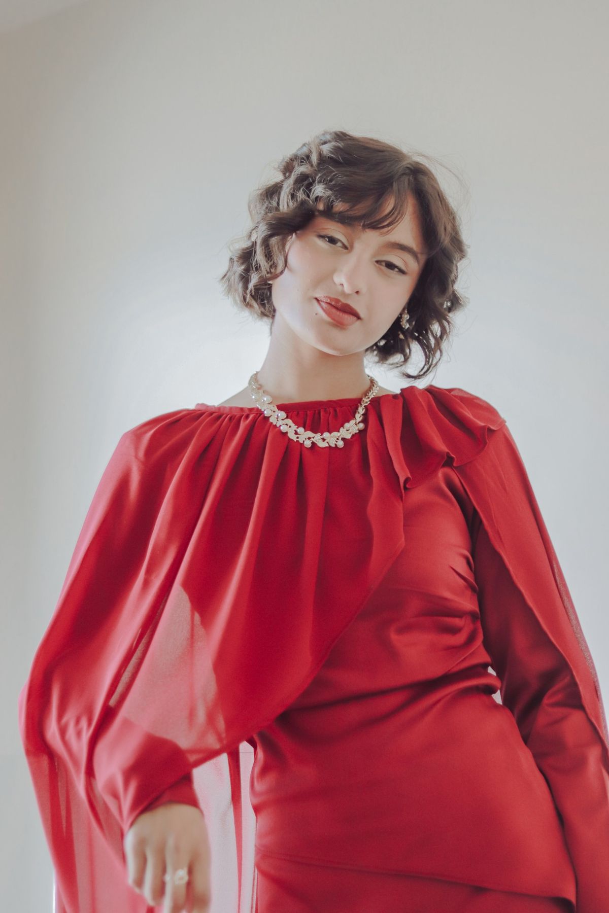 Fashion portrait of a model in a red dress with a pearl necklace