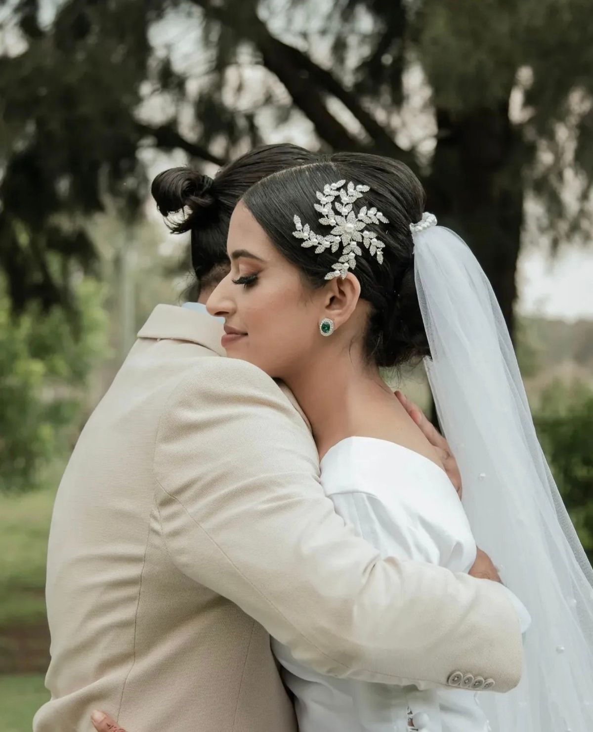 Bride with a jewelled hairpiece and veil embracing the groom