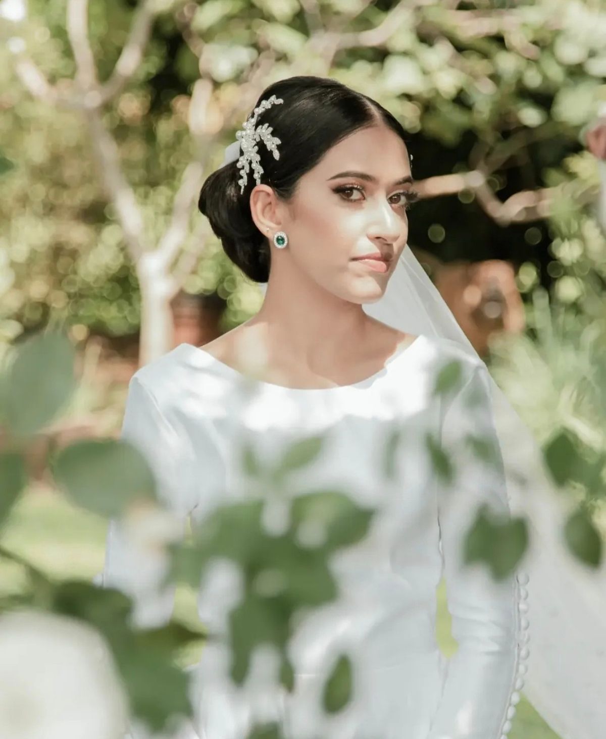 Portrait of a bride framed by leaves in a garden