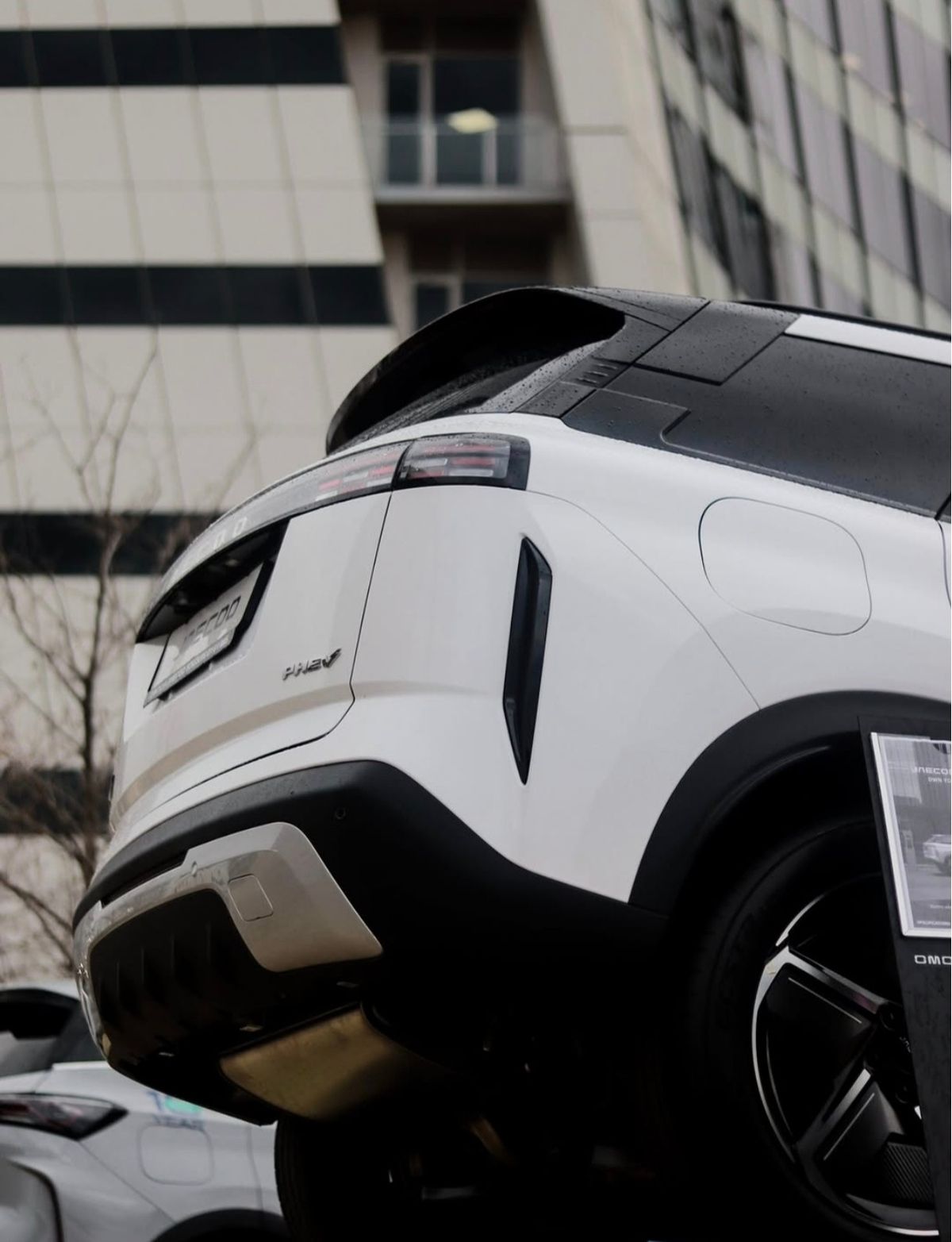 Rear three-quarter view of a white SUV with rain on the roof