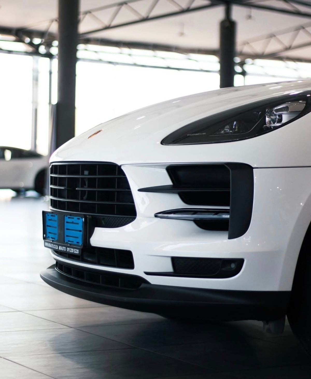 Front grille and headlight of a white SUV in a showroom