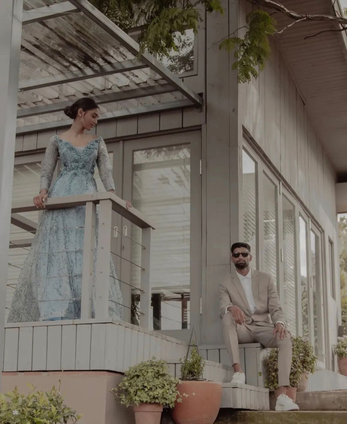 Woman in a blue gown on a balcony looking down at a man seated on the steps