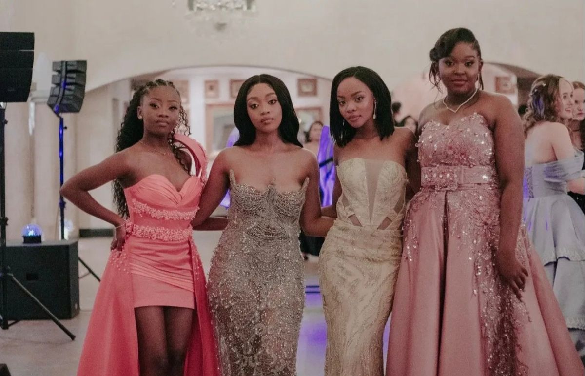 Four friends in evening gowns posing together at a matric ball
