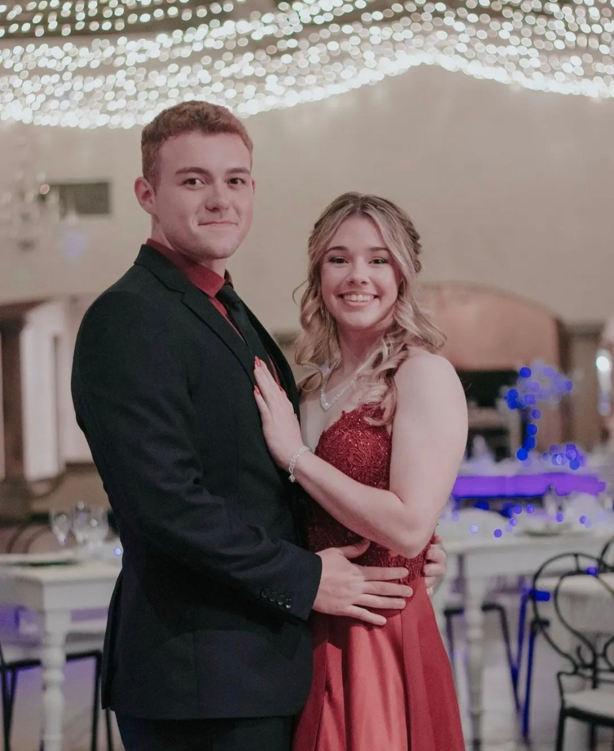 Smiling couple at a matric ball under a ceiling of fairy lights