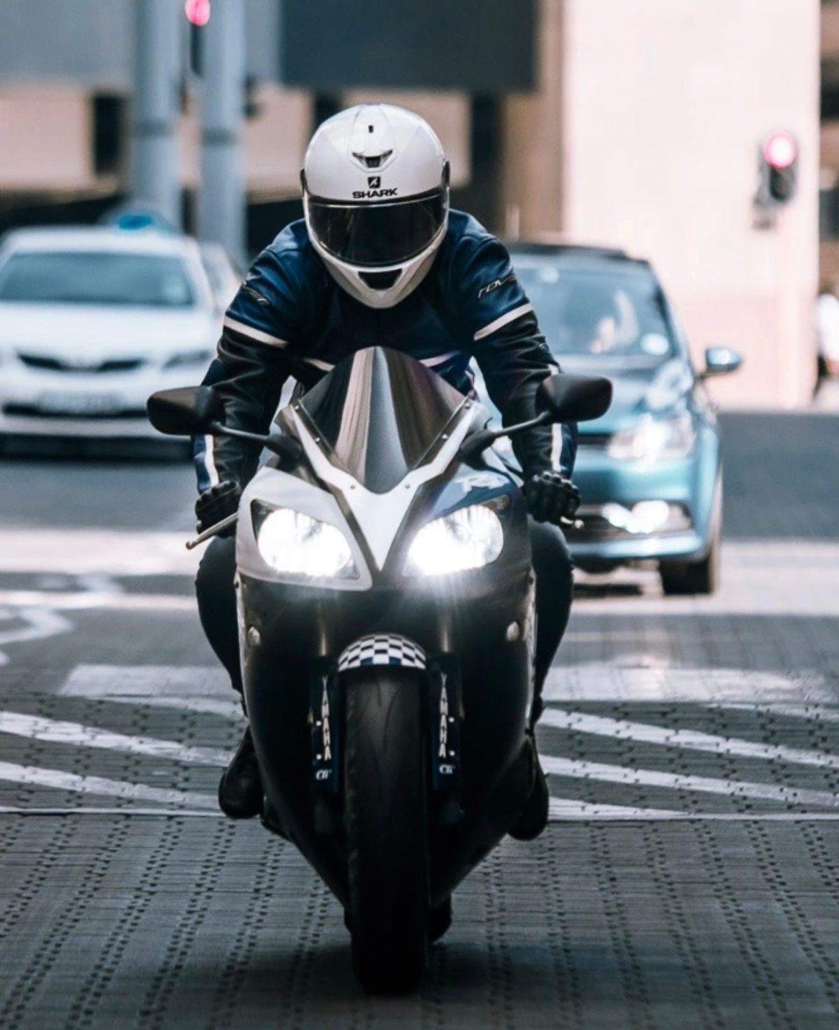 Rider on a sports bike with headlights on in city traffic