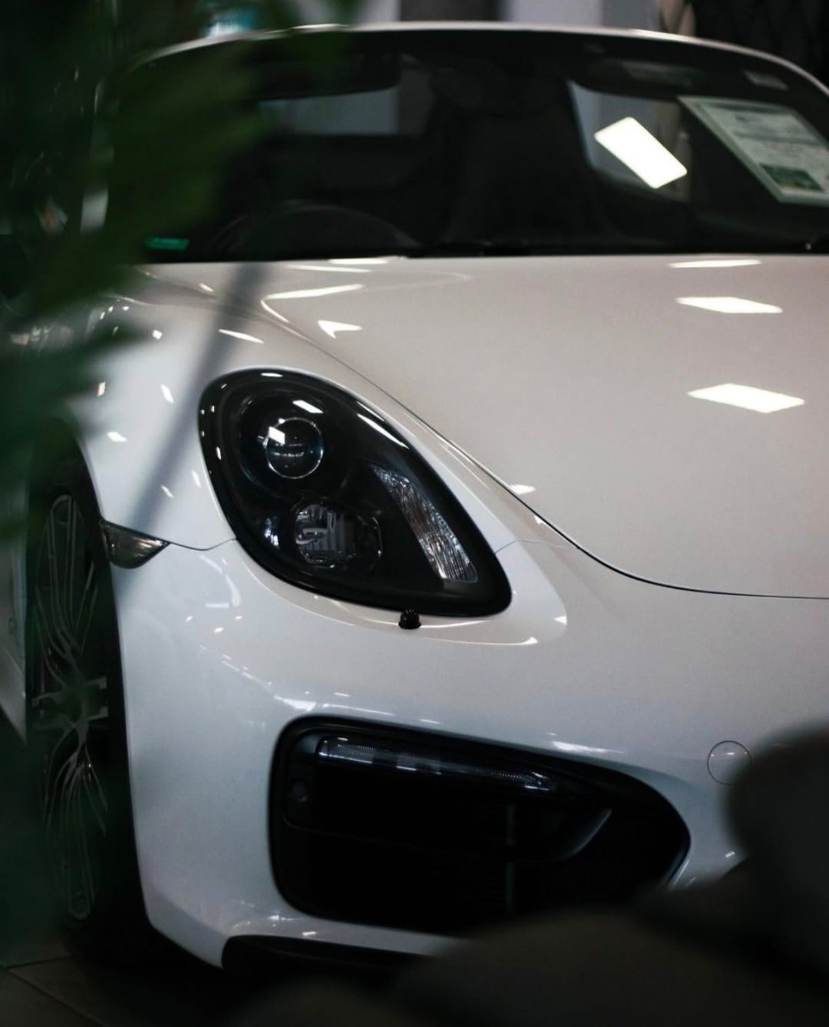 Headlight and front bumper of a white sports car in a showroom