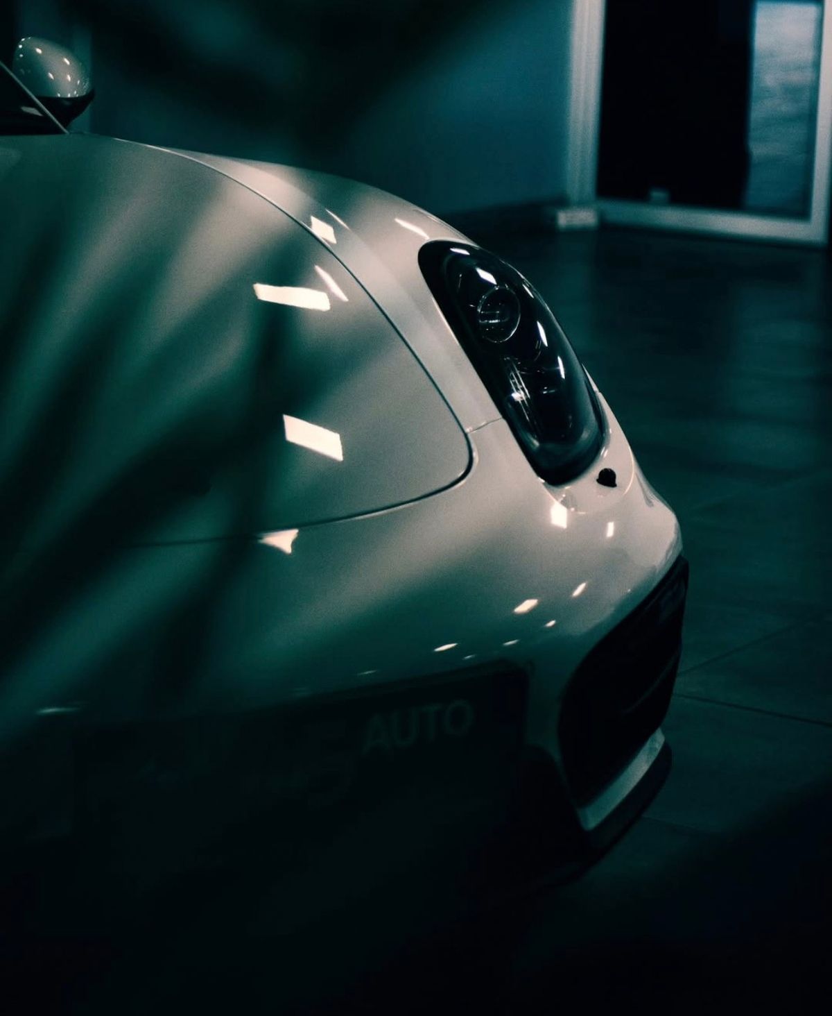 Front wing and headlight of a white sports car in low light