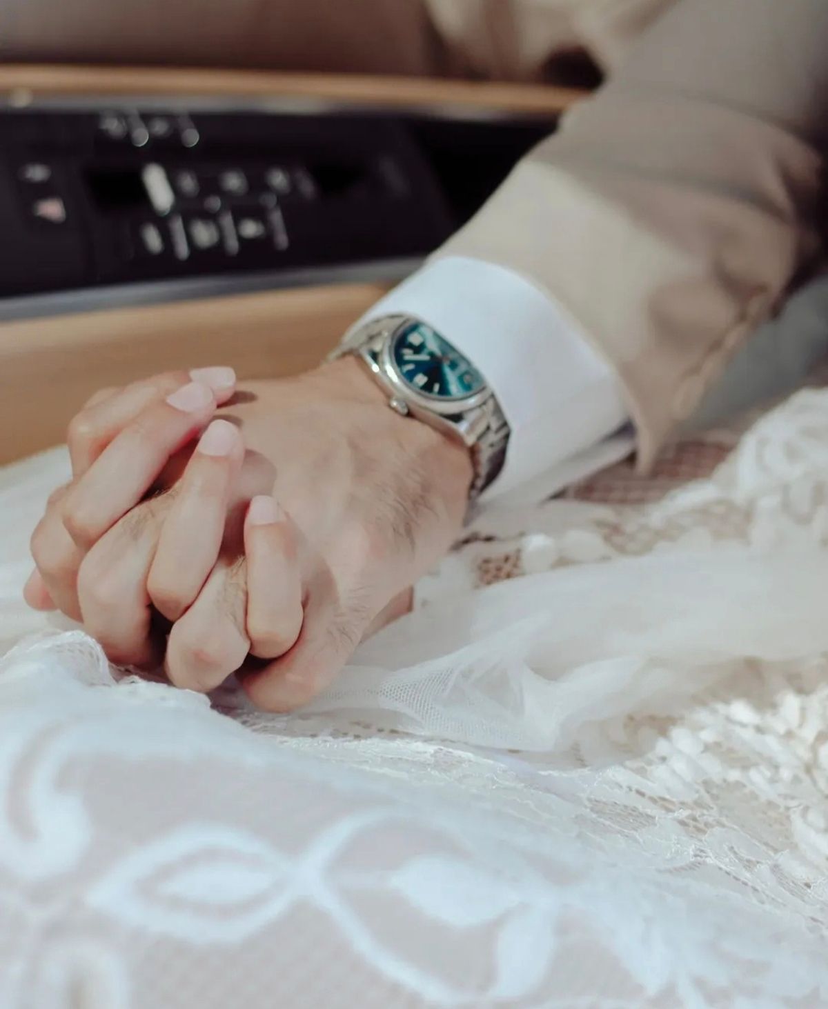 Close-up of the couple holding hands on the bride’s lace dress