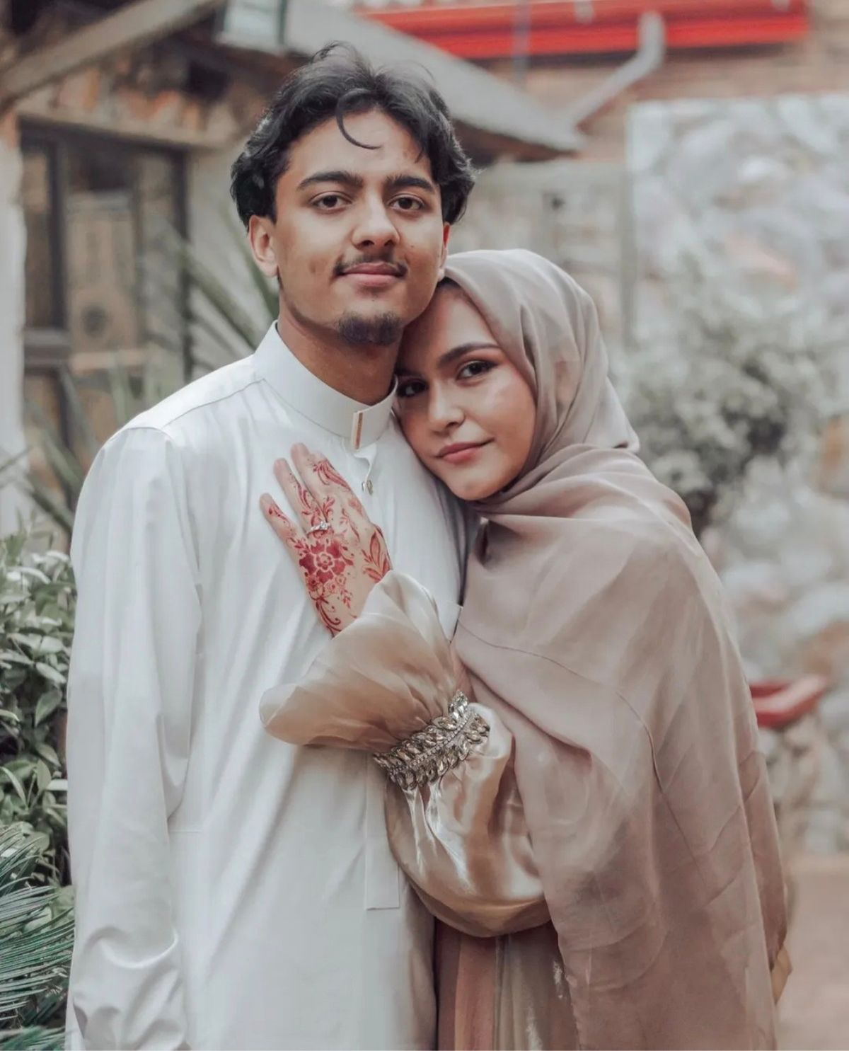 Couple standing close, her hennaed hand resting on his chest