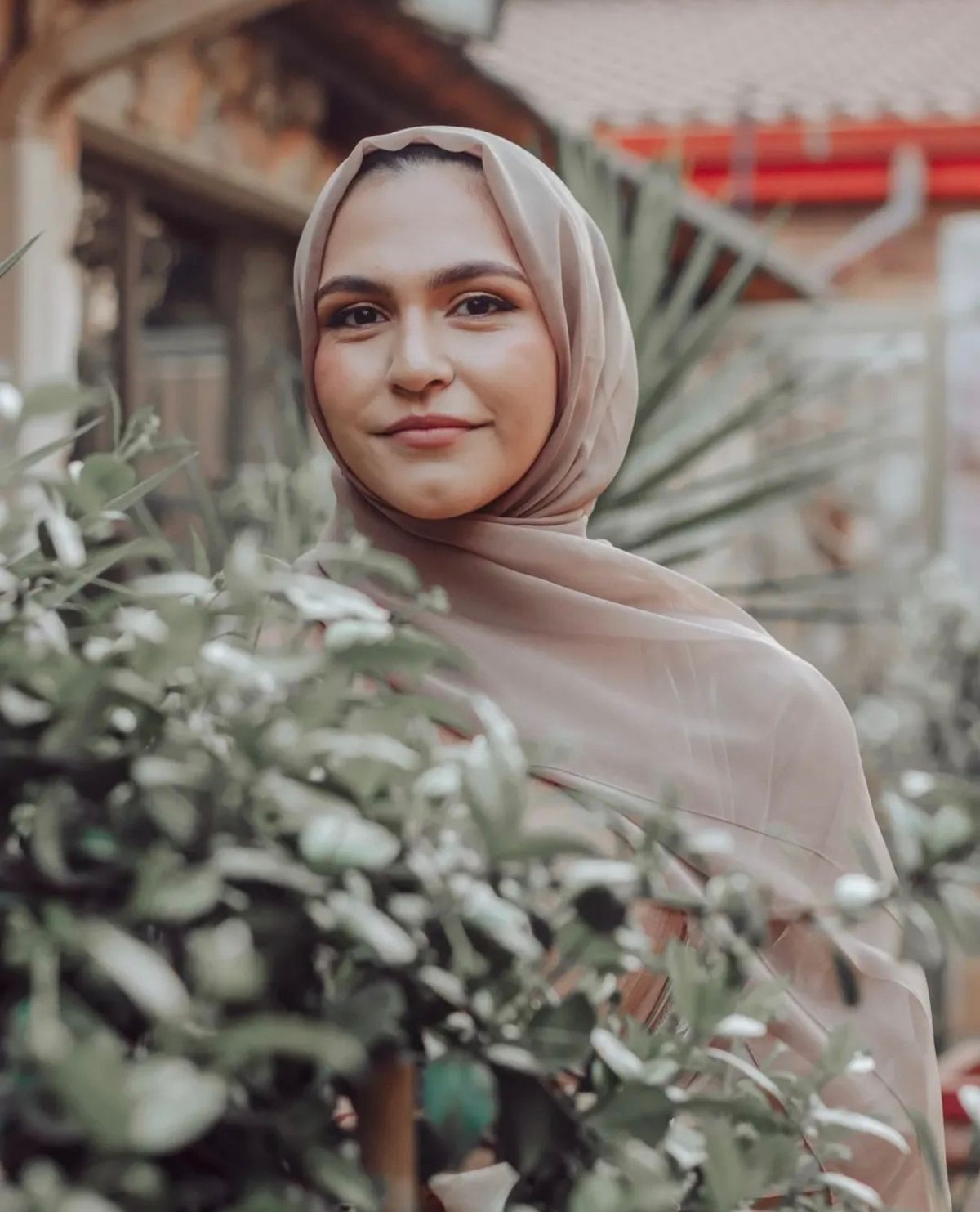 Portrait of a woman in a blush headscarf among garden greenery