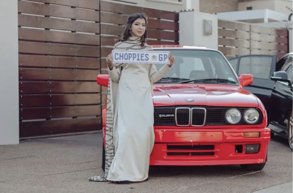 Matric ball portrait beside a red classic car