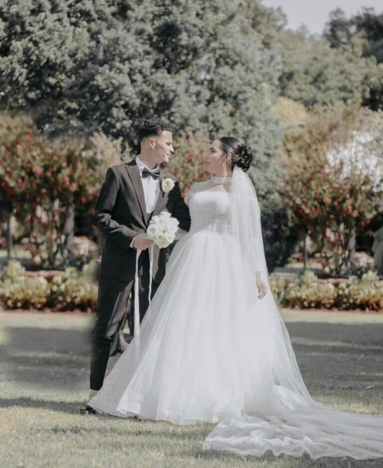 Bride and groom facing each other in a garden